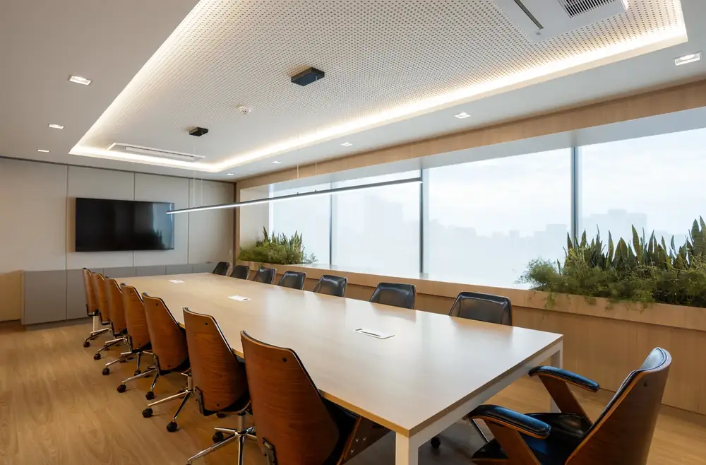 Sala de reunião com mesa longa em madeira e vista para a cidade